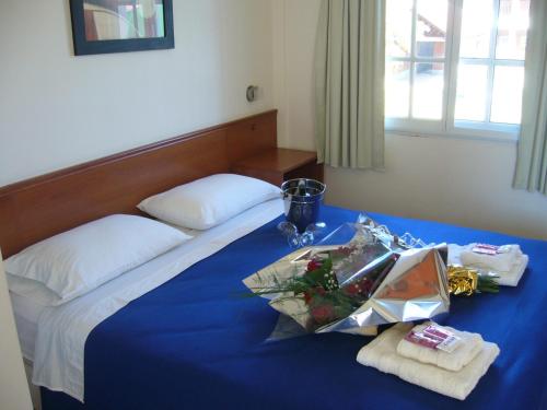 a bedroom with a bed with blue sheets and towels at Hotel Queguay in Colón
