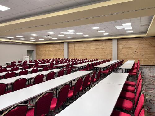 an empty lecture hall with white tables and red chairs at Hotel TENIS in Zvolen
