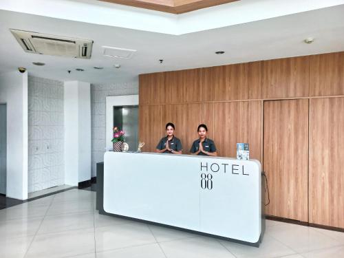 two people standing at a hotel reception desk at Hotel 88 Kedoya Jakarta in Jakarta