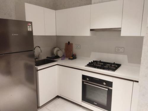 a kitchen with white cabinets and a stainless steel refrigerator at Studio Apartment at Leela Residencies. in Bengaluru