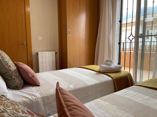 Dos camas en una habitación con ventana. en Casa con 2 apartamentos y garaje A 20 min de Sierra Nevada, en Güéjar-Sierra