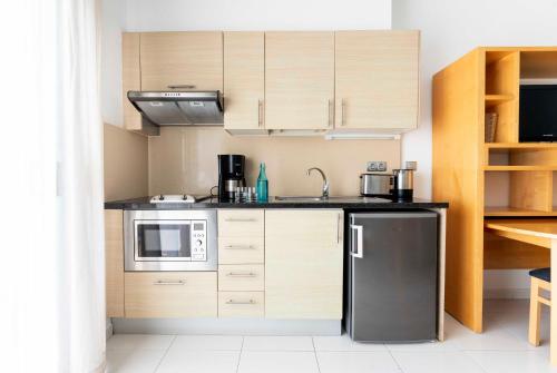 a kitchen with wooden cabinets and a black refrigerator at Ona Hollywood Mirage in Los Cristianos