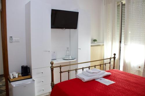 a bedroom with a red bed with a tv on the wall at BED&BREAD Piazza 'Nzegna in Carovigno