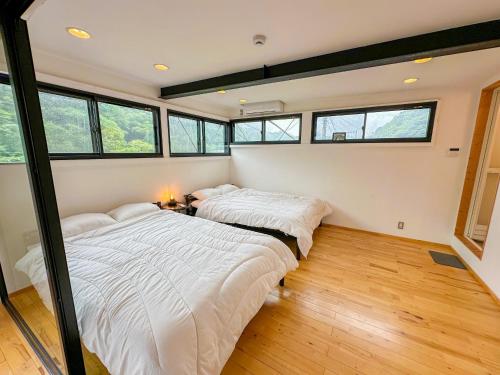 two beds in a room with windows at Eight Life Go-173ｍ2超の1棟貸し in Hayama