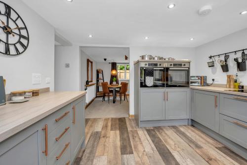 a kitchen with white cabinets and a clock on the wall at Stunning 2 Lodge Cottage retreat in Little Saxham