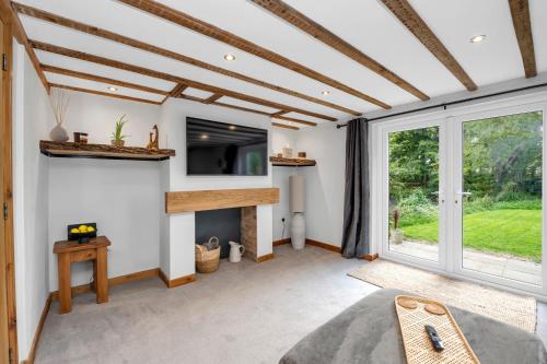 a living room with a fireplace and a large window at Stunning 2 Lodge Cottage retreat in Little Saxham
