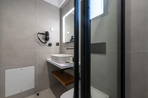 a white bathroom with a sink and a mirror at KEDL Junior Suites in Kalamata