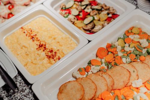 three white trays of food with vegetables in them at Hotel TENIS in Zvolen