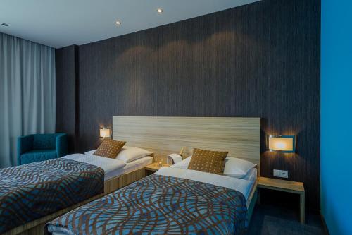 a hotel room with two beds and a blue chair at Hotel TENIS in Zvolen