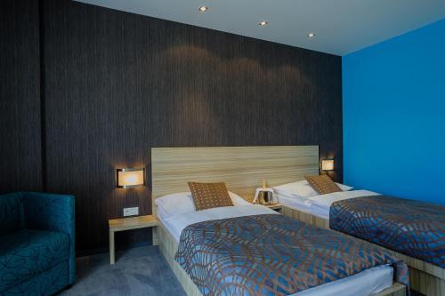 a hotel room with two beds and a chair at Hotel TENIS in Zvolen