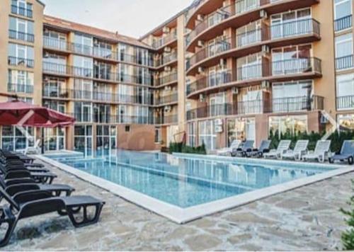 a large building with a swimming pool and chairs at Sunny view South studio Мир Авангарда in Sunny Beach