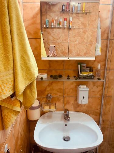 a bathroom with a sink and a yellow towel at Студия Мир Авангарда in Sunny Beach