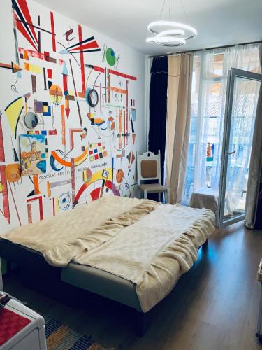 a bedroom with a bed and a colorful wall at Студия Мир Авангарда in Sunny Beach