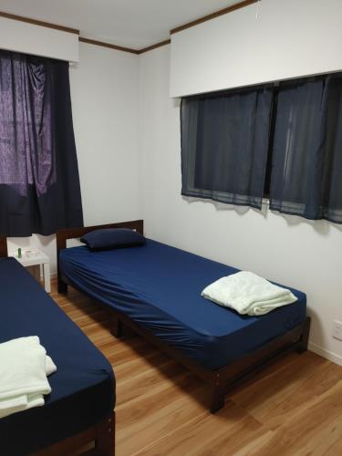2 camas en una habitación con sábanas azules y ventanas en SamuraiBeach, en Hasunuma