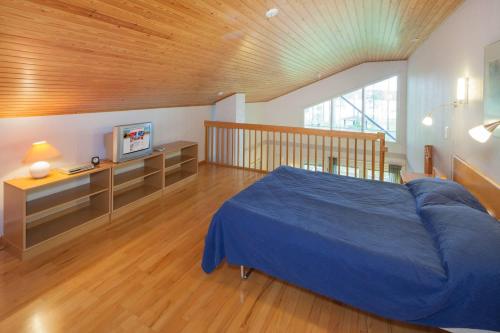 a bedroom with a blue bed and a wooden ceiling at Holiday Club Punkaharju Cottages in Kulennoinen