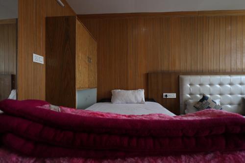 a bedroom with a bed with a red blanket on it at Sleeping Beauty Hotel Moutain view property in Joshīmath