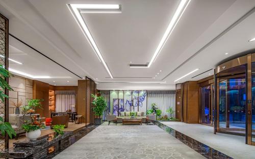 una hall di un hotel con piante sui soffitti di Metropolo Hotel Xuzhou High-speed Railway Station Jinlonghu a Xuzhou