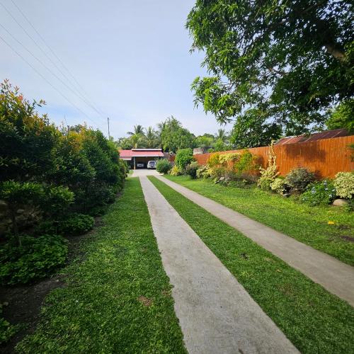 a path through a garden with a building in the background at Casa Celine Dumaguete in Dumaguete