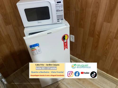 a microwave sitting on top of a refrigerator at Cabo Frio - Jardim Caiçara - Aluguel Econômico in Cabo Frio