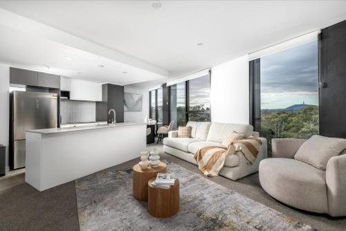 a living room with a couch and a kitchen at Elegant Retreat with Pool, Gym & Cinema in ACT in Phillip
