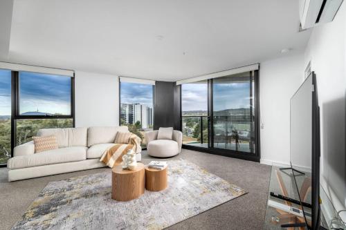 a living room with a couch and large windows at Elegant Retreat with Pool, Gym & Cinema in ACT in Phillip