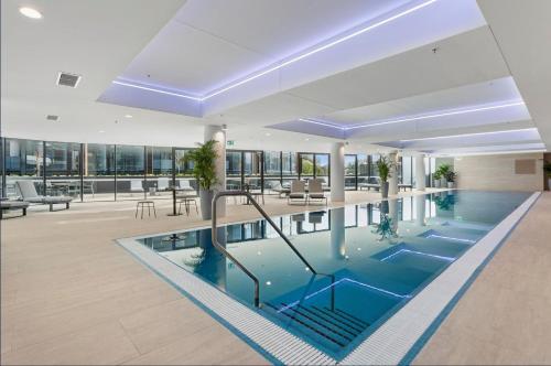 an indoor pool in a building with chairs and tables at Elegant Retreat with Pool, Gym & Cinema in ACT in Phillip
