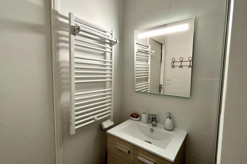 une salle de bain blanche avec un lavabo et un miroir dans l'établissement 048- Le bobo Montpelliérain - Studio - Centre, à Montpellier