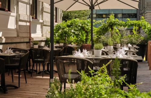 an outdoor restaurant with tables and chairs and an umbrella at Hotel Alden Splügenschloss Zürich - Leonardo Limited Edition in Zürich