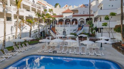 a hotel with a pool and chairs and umbrellas at Ona Beverly Hills Heights in Los Cristianos