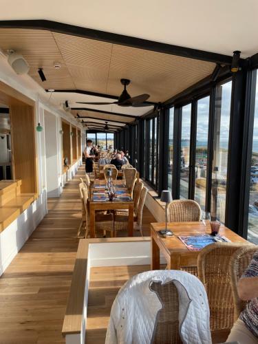 un restaurant avec des tables, des chaises et des fenêtres dans l'établissement Le Relais des Iles, à Coudeville-sur-Mer