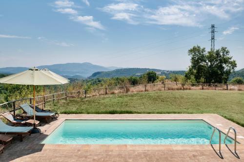 a swimming pool with an umbrella and a view of a field at Banditella in Orvieto