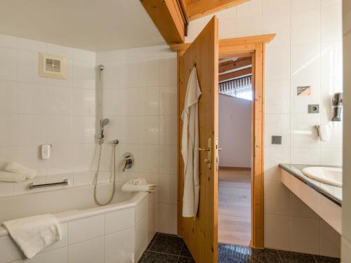 a bathroom with a tub and a sink at Hotel & Spa Sonne 4 Sterne Superior in Kirchberg in Tirol