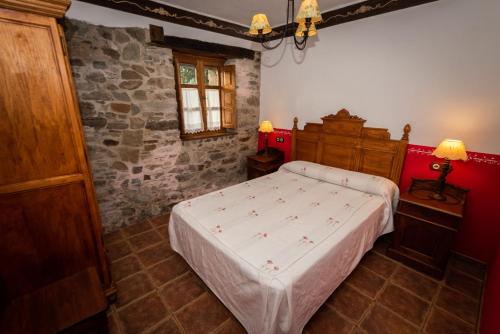 QuintanaにあるApartamentos Rurales Ca Xuacu La Antojanaの石壁のベッドルーム1室(大型ベッド1台付)
