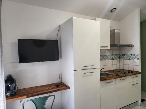 Il comprend une cuisine blanche dotée d'une télévision murale. dans l'établissement studio amande, proche gare, wifi, à Agen