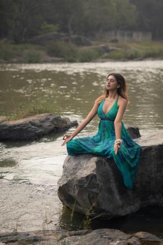 a woman in a blue dress sitting on a rock in a river at Kuruva Island Resort And Spa - By KABINI BREEZE in Mananthavady