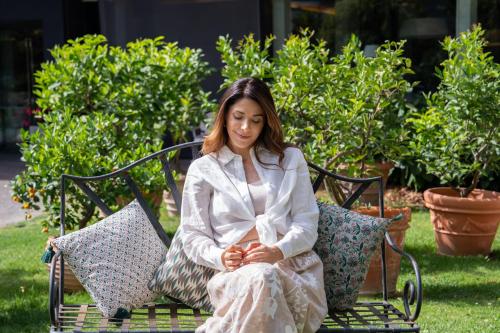 a woman in a white dress sitting on a bench at Plaza Hotel Abano Terme in Abano Terme