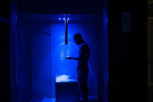 a man standing in a dark room looking at his cell phone at Plaza Hotel Abano Terme in Abano Terme