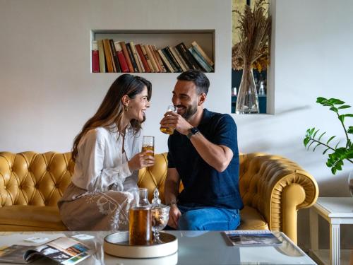 a man and woman sitting on a couch drinking beer at Plaza Hotel Abano Terme in Abano Terme