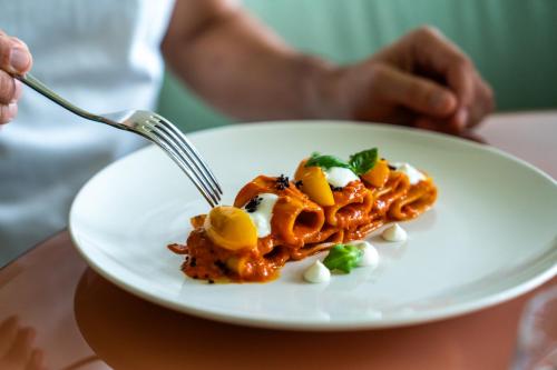 a person eating a plate of pasta with a fork at Plaza Hotel Abano Terme in Abano Terme