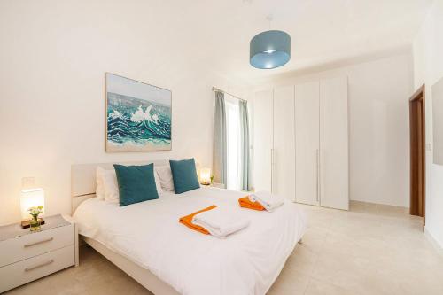 a bedroom with a large white bed with blue pillows at Hillock Residence Apartments in Marsalforn
