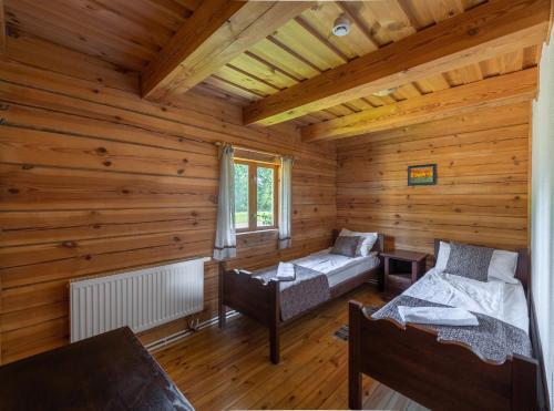 a log cabin with two beds and a couch at Sporto ir poilsio centras KORNEALITA IEVALAUKIS in Gaveikėnai