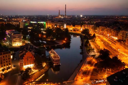 a view of a city at night with a river at Great Polonia River Boat Apartments Wrocław in Wrocław