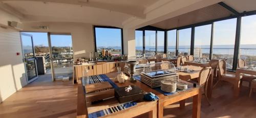 ein Esszimmer mit Tisch und Stühlen und Fenstern in der Unterkunft Le Relais des Iles in Coudeville