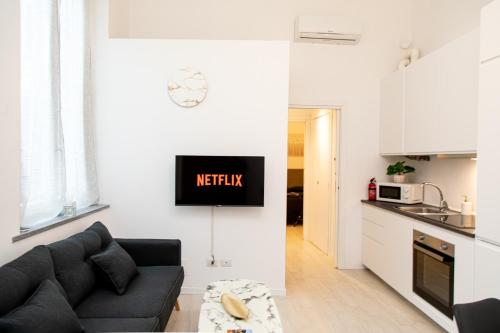 Una sala de estar con un sofá y una cocina. en Pavia - Esclusivo appartamento in pieno centro, en Pavia