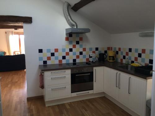 a kitchen with white cabinets and a stove top oven at Domaine La Barbe ! in Lalanne-Arqué