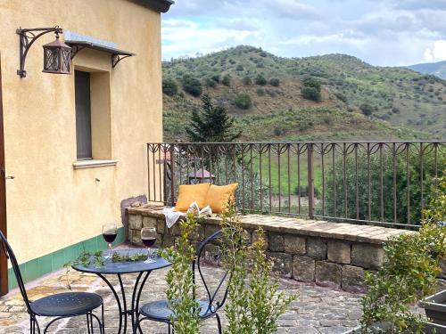 a patio with two chairs and a table with wine glasses at Azienda Agrituristica Bergi in Castelbuono
