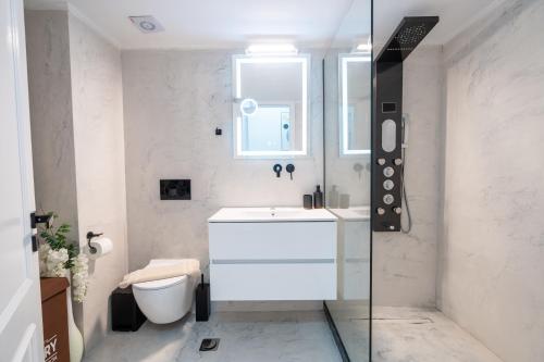 a white bathroom with a sink and a toilet at VDG Seafront Elegant Residence in Rethymno Town