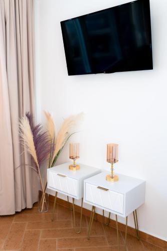 a living room with two white tables and a tv at VDG Seafront Elegant Residence in Rethymno Town