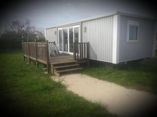 a house with a deck with a chair on it at DOMAINE DE LA GRANGE DES CHAMPS in Lorris