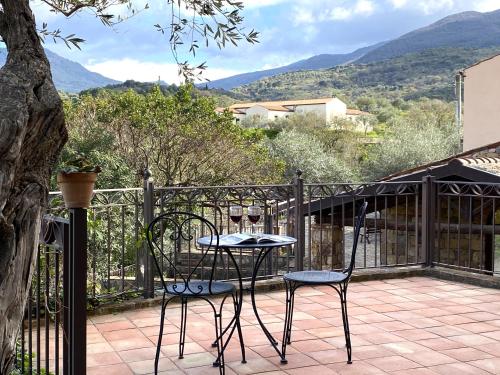 two chairs and a table on a balcony with mountains at Azienda Agrituristica Bergi in Castelbuono